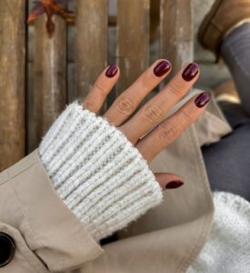 Mão de pele clara, com unha curta e arredondada burgundy