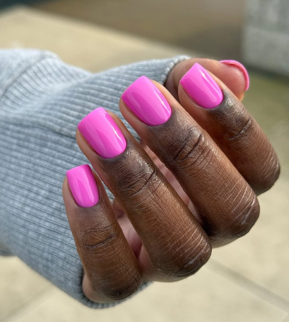 Mão de pele preta, com unha curta e quadrada rosa-chiclete