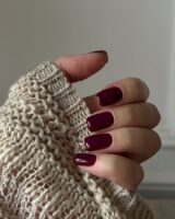 Mão de pele clara, com unha quadrada burgundy