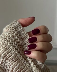 Mão de pele clara, com unha quadrada burgundy