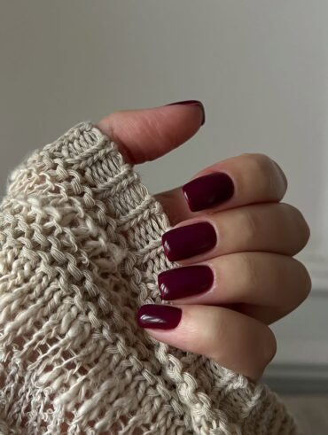 Mão de pele clara, com unha quadrada burgundy
