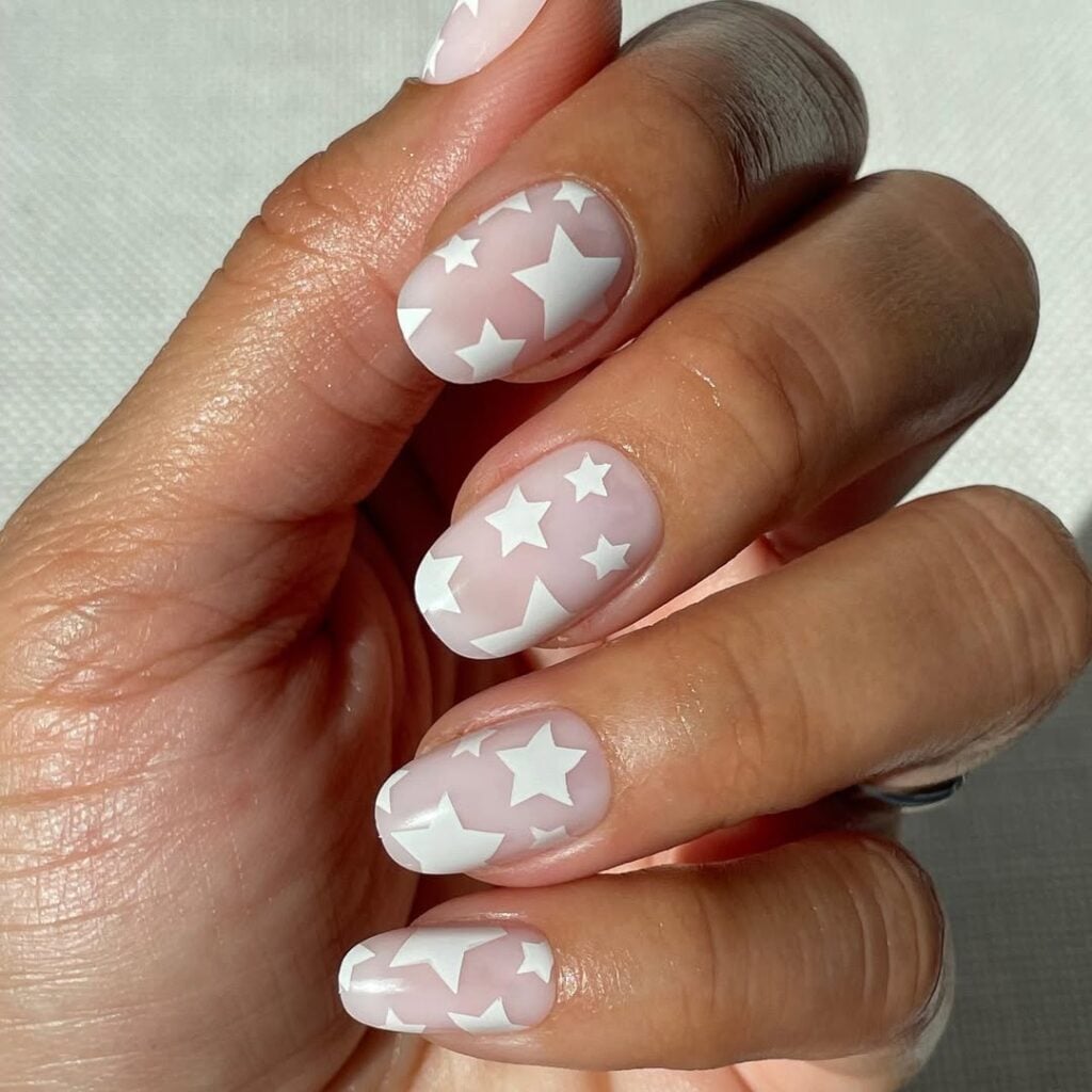 Mão de pele clara, com unha squoval clara com estrelas