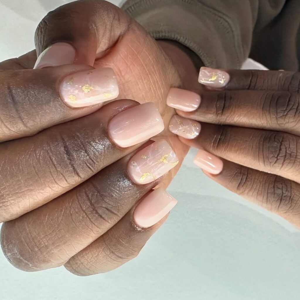Mãos de pele preta, com unha squoval nude com brilho