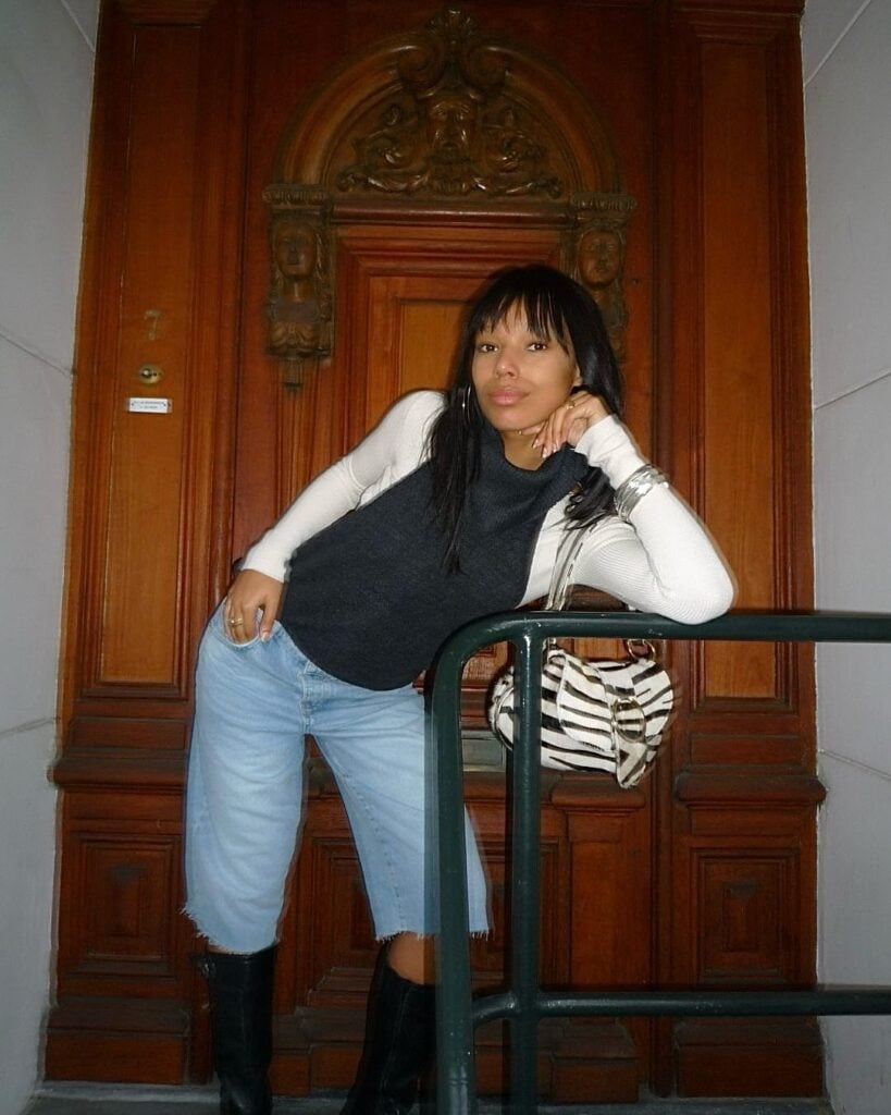 Mulher jovem com colete, suéter, bermuda jens, botas e bolsa animal print de zebra