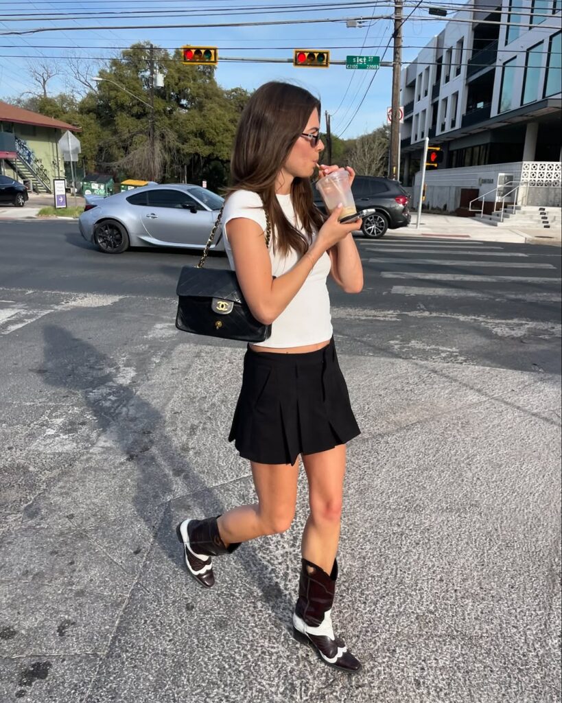 Mulher jovem e magra com look preto e branco e botas animal print