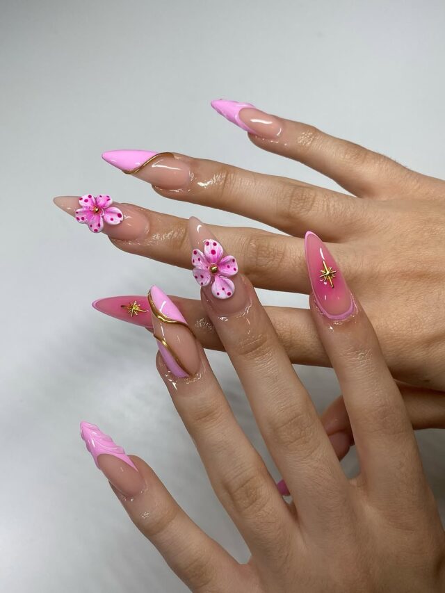 Mão de pele clara, com unha amendoada rosa com aplicações e detalhes em dourado
