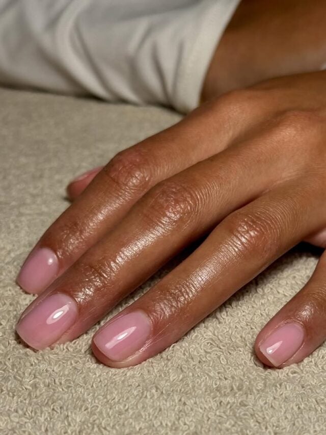 Mão de pele branca com unha curta com esmalte rosa-claro