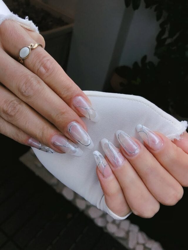 Mão de pele branca, com unha longa e amendoada, com nail art cromada prata