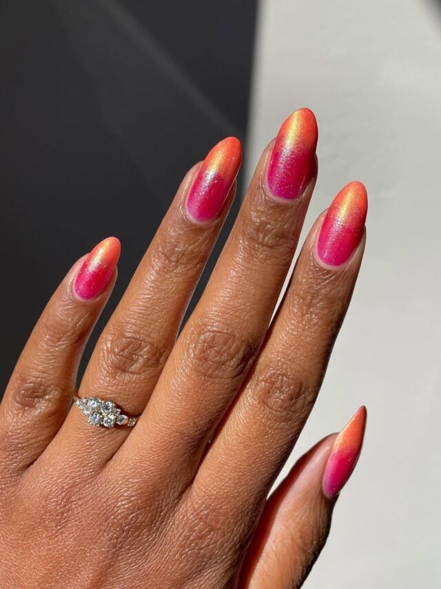 Mão de pele preta, com anel em prata e unha amendoada rosa com degradê laranja