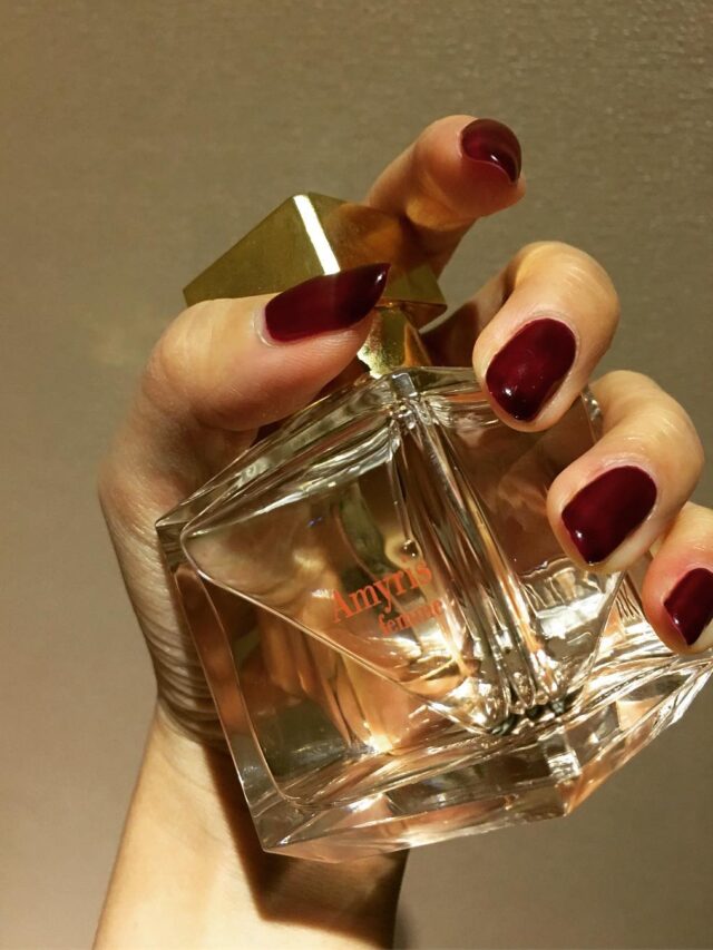 Mão de pele branca com unha vermelha elegante com esmalte Wine OPI