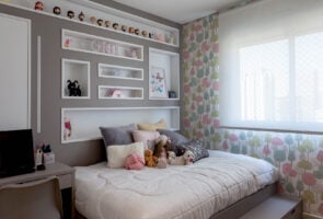 Quarto infantil com cama espaçosa e nichos na cabeceira com enfeites