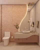 Banheiro em tons de rosa e branco, com cuba curva, espelho orgânico com led e revestimento em granilite