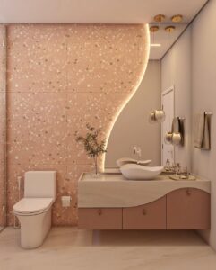 Banheiro em tons de rosa e branco, com cuba curva, espelho orgânico com led e revestimento em granilite