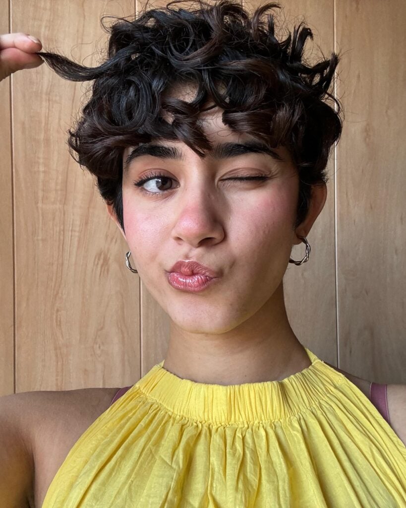 Mulher branca com cabelo curto, no estilo bixie e cacheado