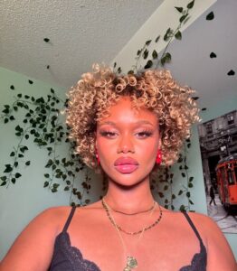 Mulher negra com cabelo curto, no estilo bob e cacheado