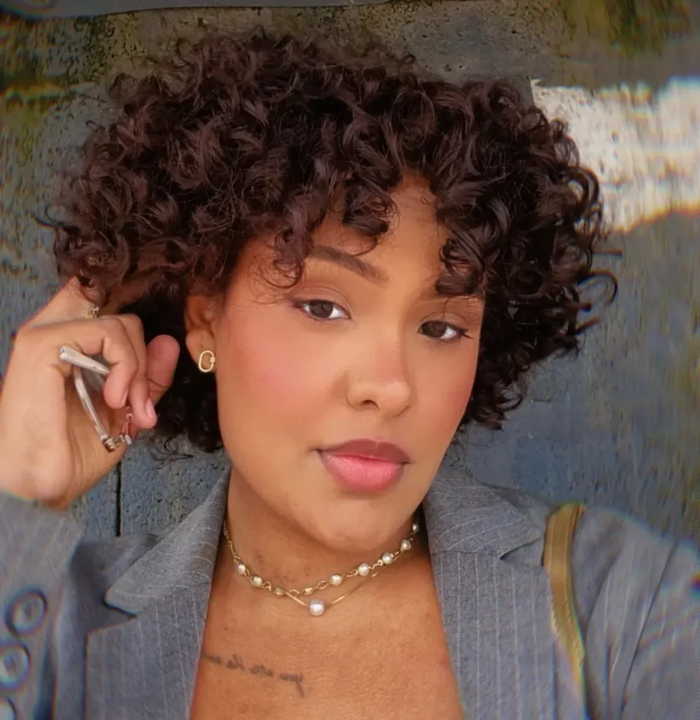 Mulher negra com cabelo curto e cacheado na cor chocolate com franja