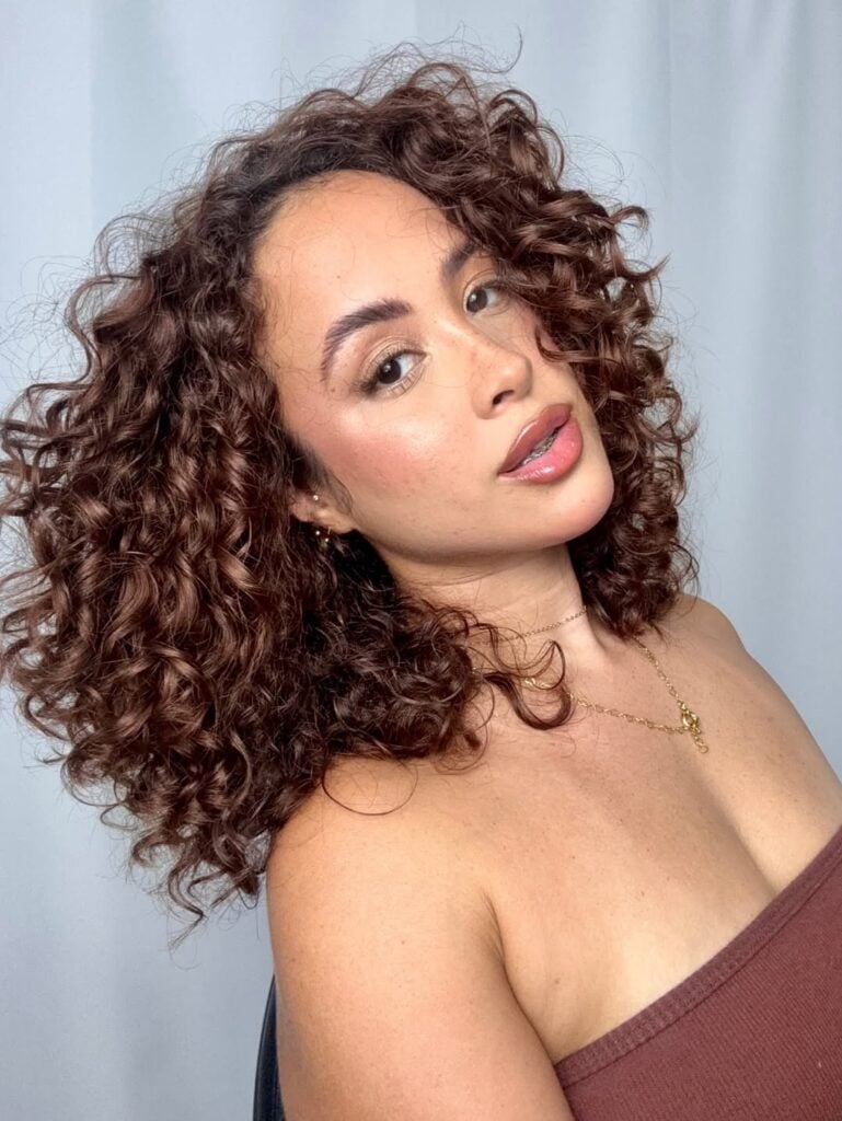 Mulher branca com cabelo médio e cacheado na cor chocolate