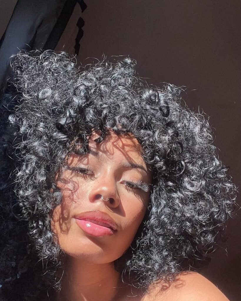 Mulher de pele preta, com cabelo cacheado escuro