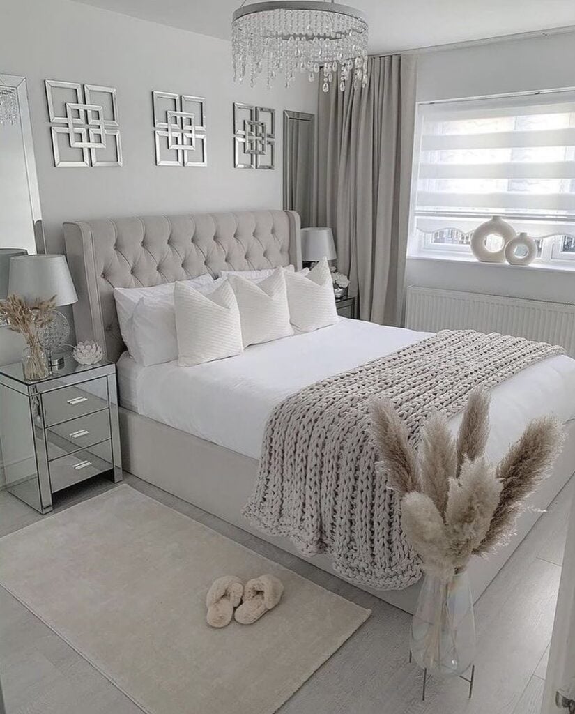 Quarto de casal em tons neutros, com lustra, cabeceira em capitonê e manta de tricô