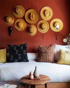 Sala de estar com parede terracota e chapéus de palha pendurados