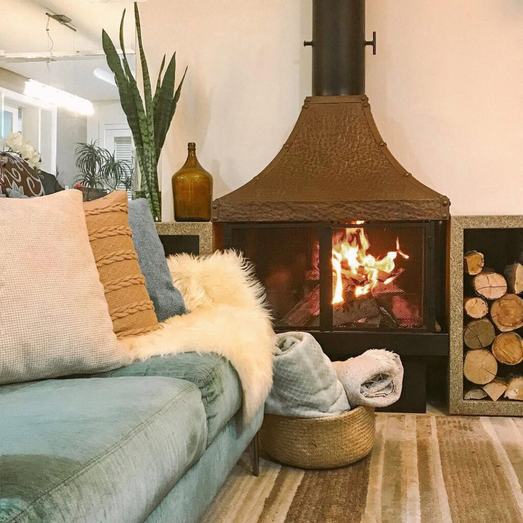 Sala com lareira, sofá de veludo, almofadas e manta