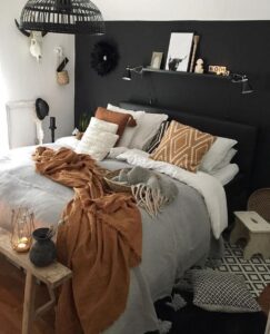 Quarto com parede e cabeceira preta, roupa de cama branca, marrom e cinza