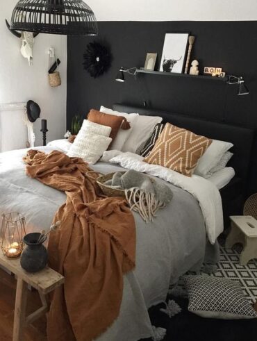 Quarto com parede e cabeceira preta, roupa de cama branca, marrom e cinza