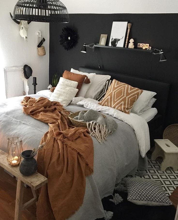 Quarto com parede e cabeceira preta, roupa de cama branca, marrom e cinza