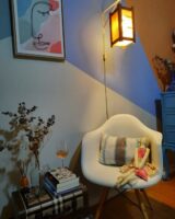 Cantinho relaxante com poltrona orgânica branca, luminária de chão, livros ao lado da poltrona