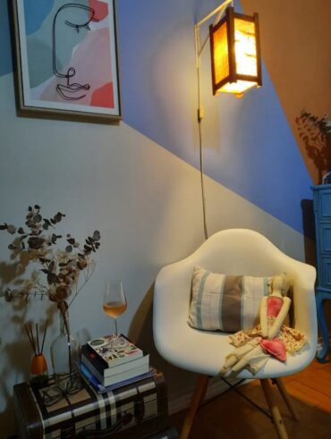 Cantinho relaxante com poltrona orgânica branca, luminária de chão, livros ao lado da poltrona