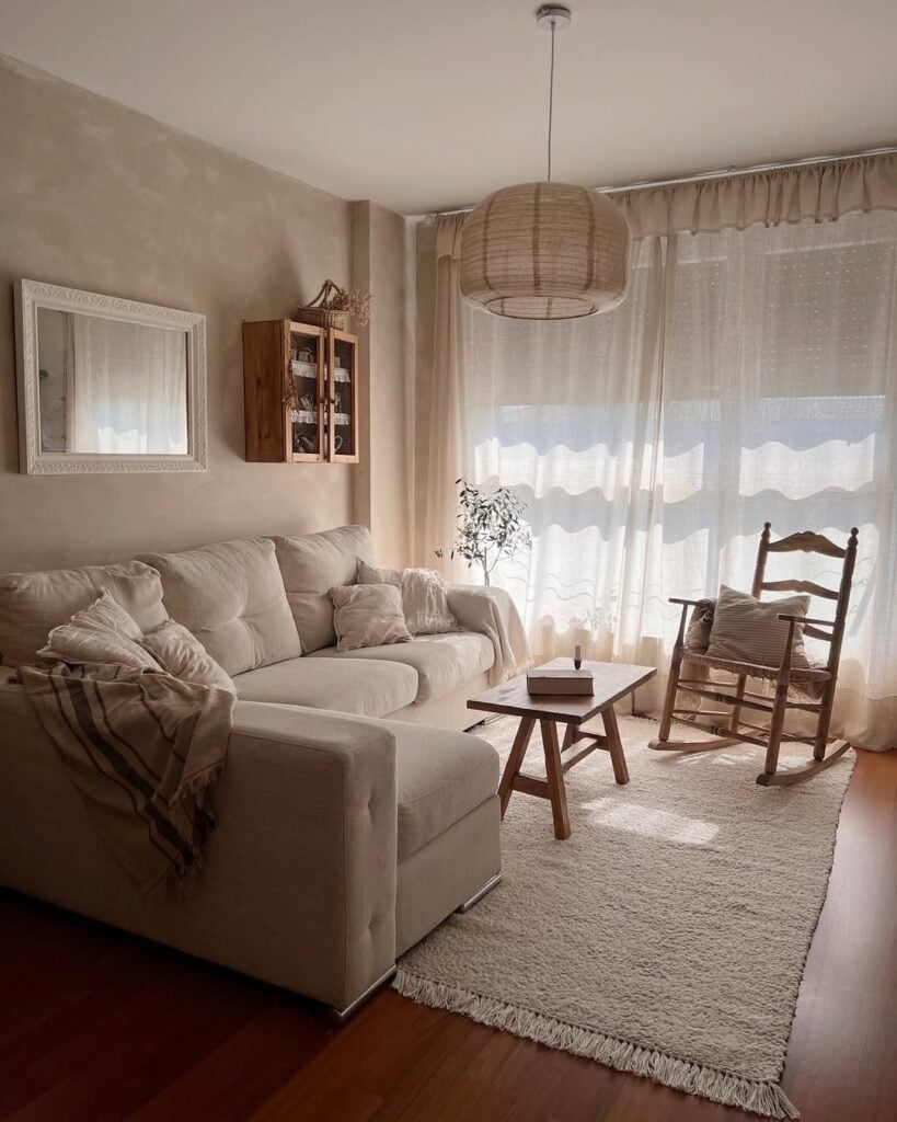 Sala de estar com paleta de tons neutros, mesa de centro e cadeira de balanço de madeira