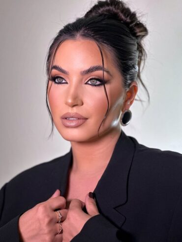 Mulher de pele clara, com blazer preto, cabelo preso e maquiagem com lápis preto