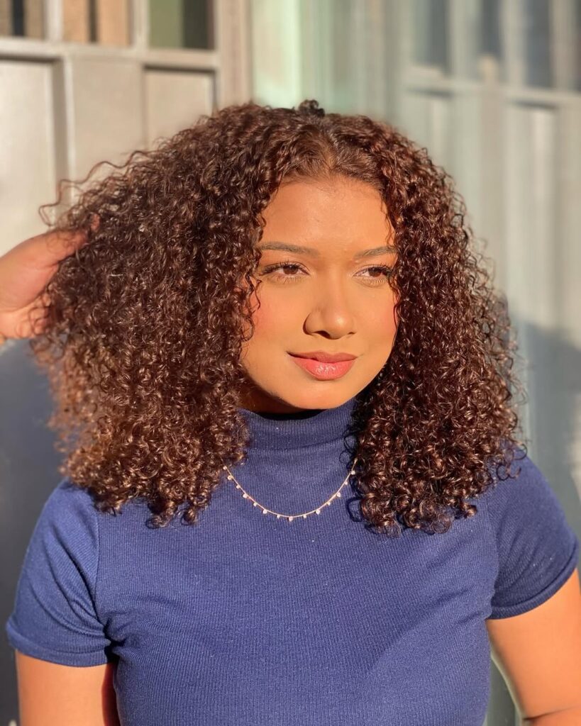 Mulher negra com cabelo médio e cacheado na cor chocolate