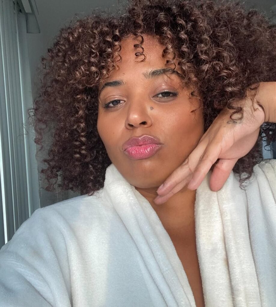 Mulher negra com cabelo médio e cacheado na cor chocolate com franja