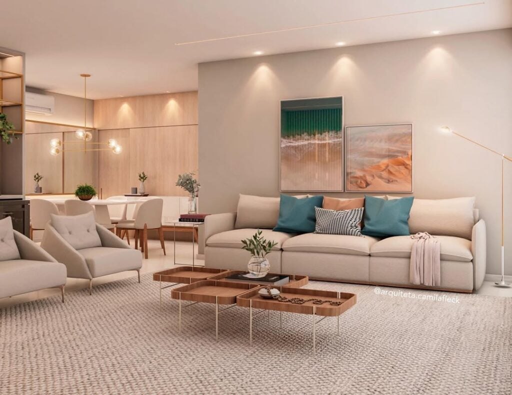 Sala ampla com poltronas e sofá bege, com quadros e almofadas coloridas