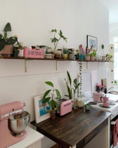 Cozinha decorada com prateleira e balcão com torradeira e batedeira Smeg com plantas