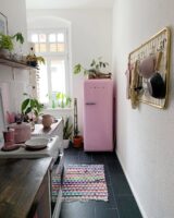 Cozinha decorada com geladeira rosa e tapete