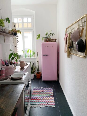 Cozinha decorada com geladeira rosa e tapete