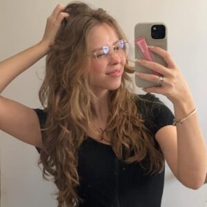 Mulher de pele clara, com blusa preta e cabelo loiro ondulado