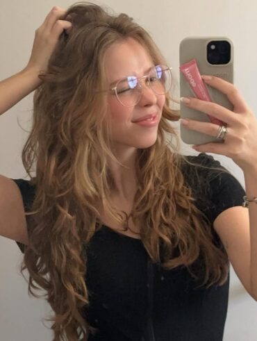 Mulher de pele clara, com blusa preta e cabelo loiro ondulado