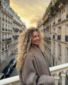 Mulher de pele clara, com casaco e cabelo cacheado loiro