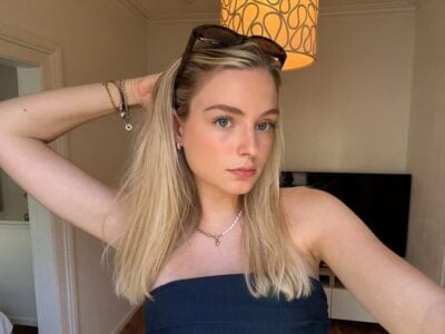 Mulher de pele clara, com tube top preto, cabelo loiro, óculos de sol e acessórios em prata/dourado