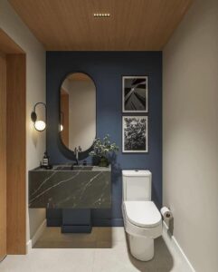 Lavabo com parede azul, espelho oval e quadros com bordas brancas