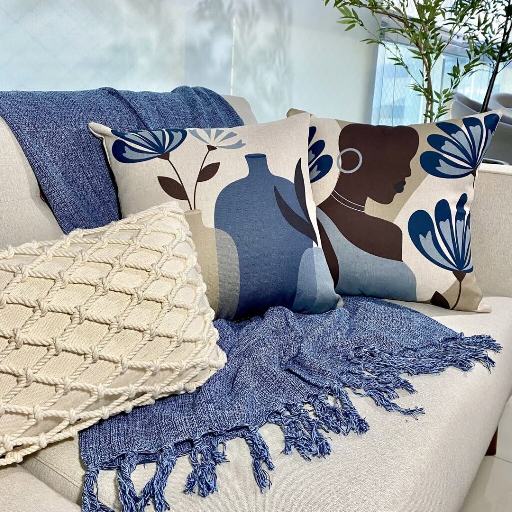 Sofá claro com manta azul combinando com as estampas das almofadas
