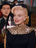 Marilyn Monroe, com rouba preta com animal print e maquiagem clássica