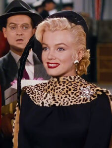 Marilyn Monroe, com rouba preta com animal print e maquiagem clássica