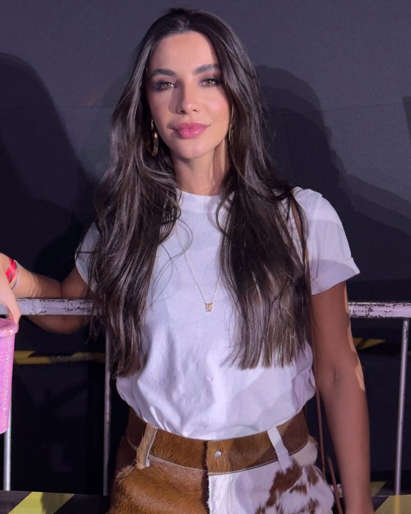 Mulher de pele clara, com cabelo castanho, blusa branca e maquiagem perfeita
