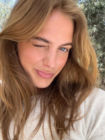 Mulher de pele clara, com blusa branca e cabelo loiro