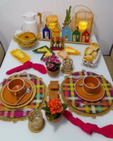Mesa posta junina com recipientes em formato de bandeirinhas, sousplat xadrez e enfeite com igrejinhas