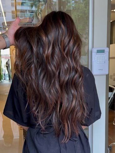 Mulher com cabelo longo, ondulado e com luzes na técnica morena iluminada na cor chocolate